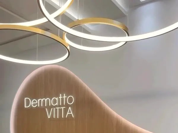 A recepção com os anéis de luz e o logo Dermatto Vitta na parede de madeira